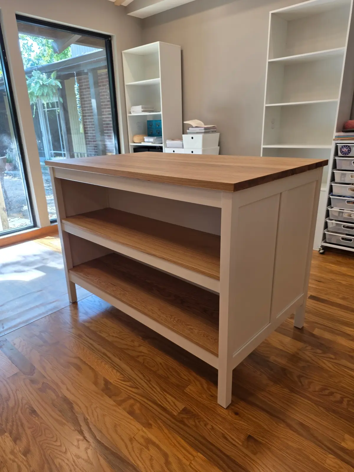 Completed freestanding white kitchen island with wood top and aligned open shelves