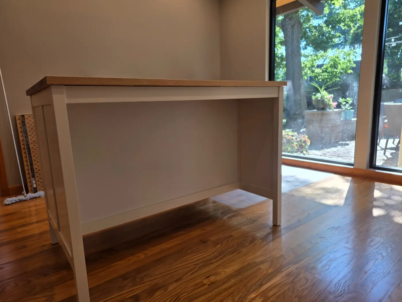 Back side of an assembled freestanding white kitchen island with wood top