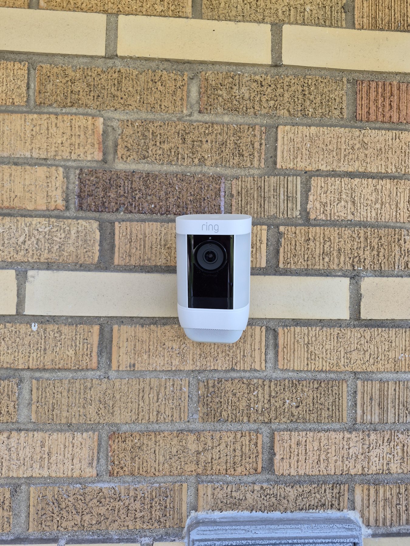 Front view of a Ring security camera securely mounted on a brick exterior wall